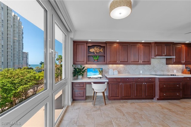 kitchen with stone finish floor, tasteful backsplash, open shelves, built in desk, and light countertops