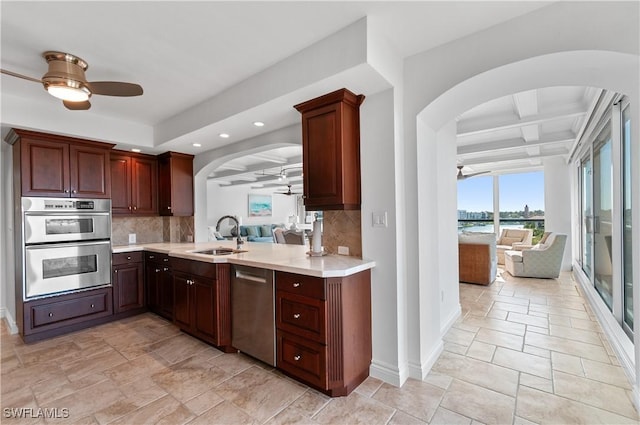 kitchen featuring a ceiling fan, a sink, appliances with stainless steel finishes, and arched walkways