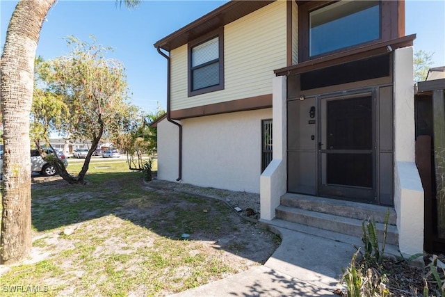 doorway to property with stucco siding and a lawn