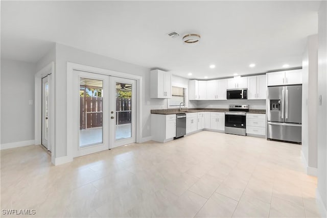 kitchen with recessed lighting, a sink, stainless steel appliances, french doors, and dark countertops