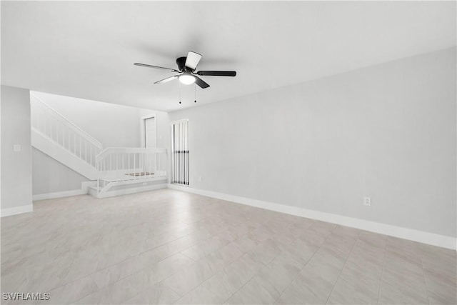 unfurnished living room featuring stairs, a ceiling fan, and baseboards