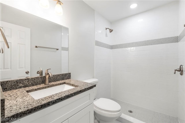 full bathroom with vanity, toilet, and tiled shower