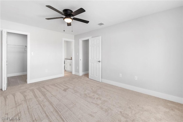 unfurnished bedroom featuring a spacious closet, visible vents, baseboards, carpet, and a closet