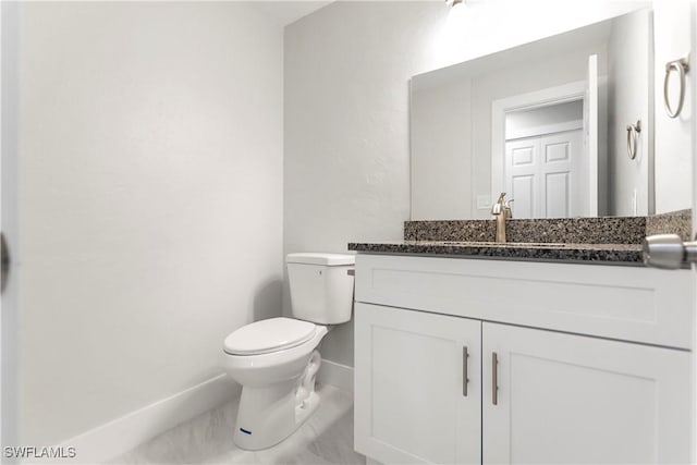 half bath with vanity, toilet, and baseboards