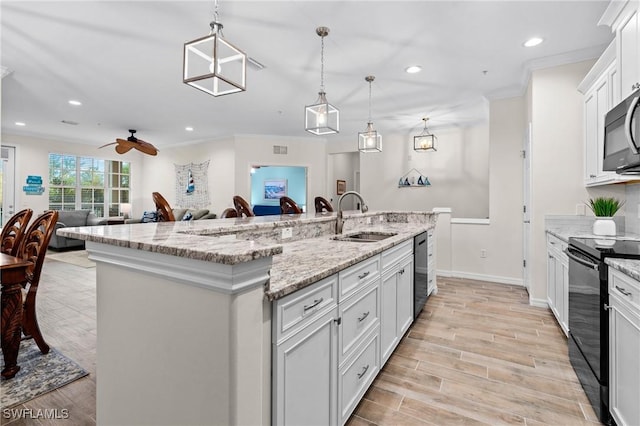 kitchen with light wood finished floors, crown molding, a center island with sink, black electric range oven, and a sink