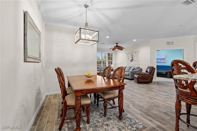 dining space featuring ornamental molding, wood finished floors, visible vents, and baseboards