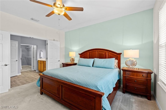 bedroom with a ceiling fan, baseboards, visible vents, light colored carpet, and connected bathroom