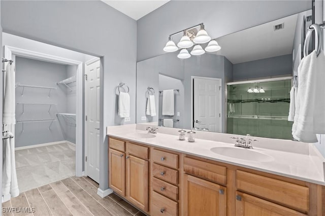 full bathroom with double vanity, visible vents, a shower stall, and a sink