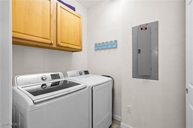 washroom featuring electric panel, baseboards, cabinet space, and separate washer and dryer