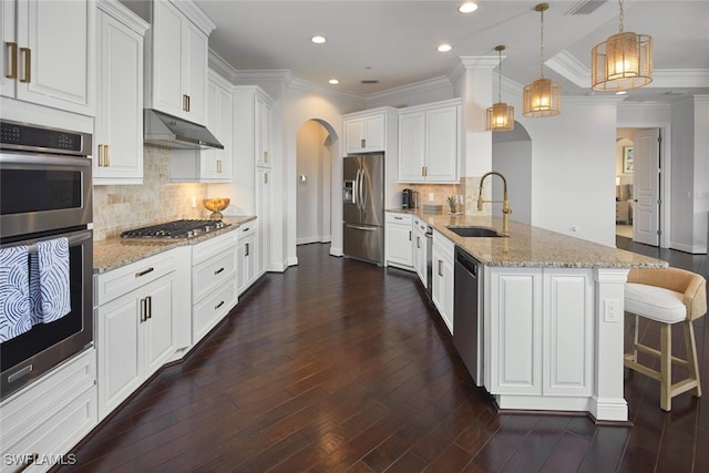 kitchen featuring under cabinet range hood, a peninsula, arched walkways, stainless steel appliances, and a sink