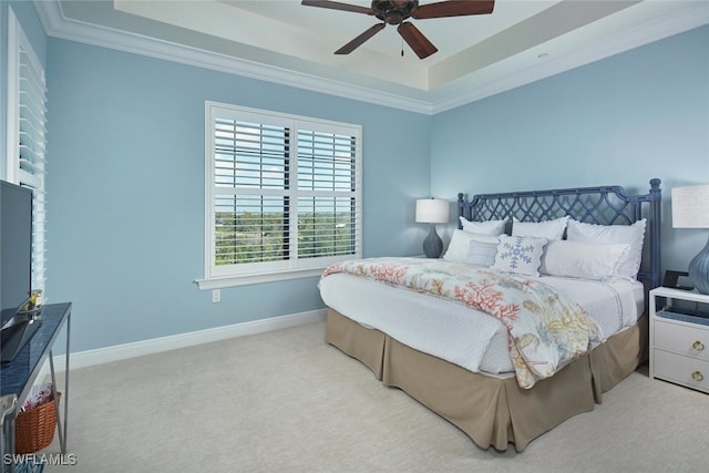 bedroom featuring baseboards, carpet floors, a tray ceiling, ceiling fan, and crown molding