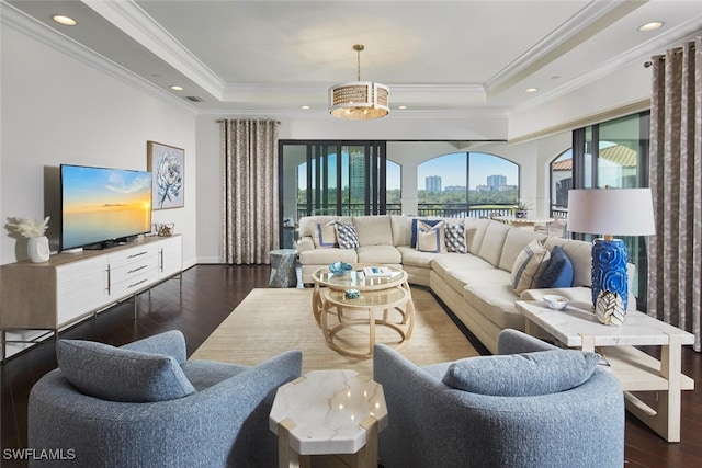 living room with a wealth of natural light, recessed lighting, dark wood finished floors, and a tray ceiling