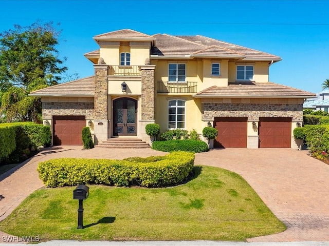 view of front of home featuring stone siding, french doors, and decorative driveway