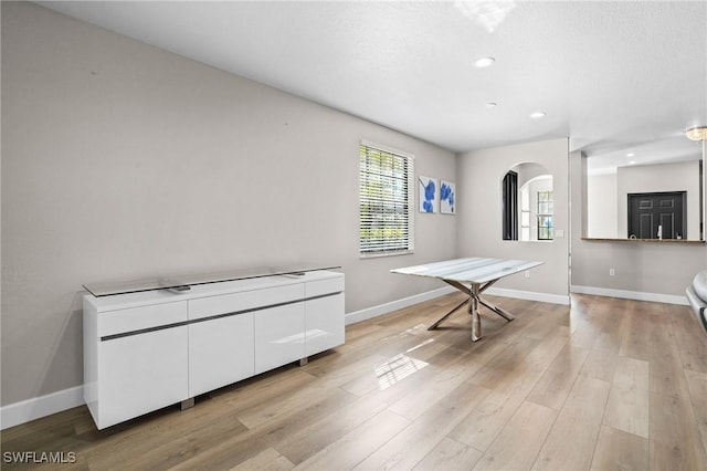 interior space featuring recessed lighting, baseboards, light wood-style floors, and arched walkways