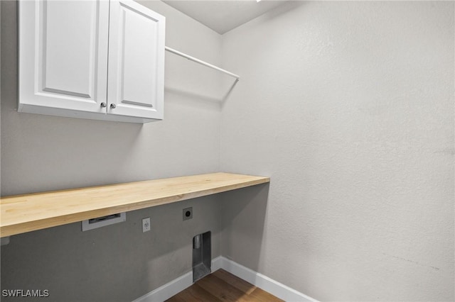 clothes washing area with baseboards, cabinet space, hookup for an electric dryer, and dark wood-style floors