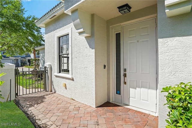 entrance to property with stucco siding and a gate