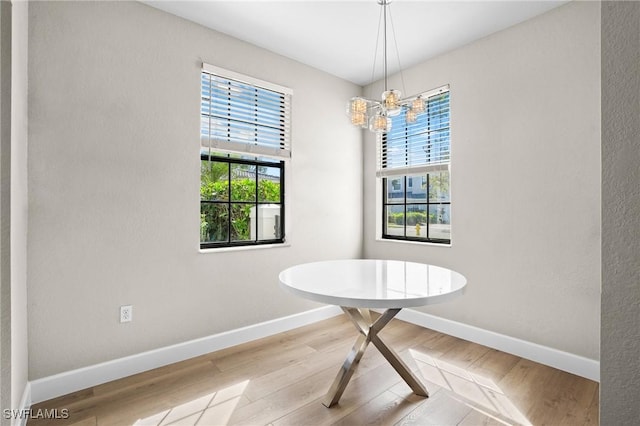 dining room featuring a chandelier, baseboards, and wood finished floors