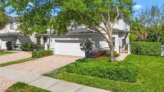 view of property hidden behind natural elements with stucco siding, an attached garage, decorative driveway, and fence