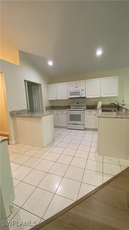 kitchen with white appliances, white cabinetry, a sink, and light tile patterned flooring