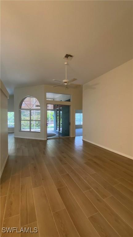 unfurnished living room featuring baseboards, ceiling fan, visible vents, and wood finished floors