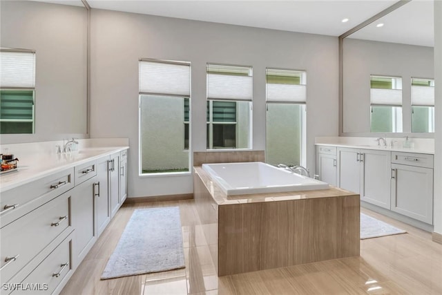 full bathroom featuring a bath, two vanities, and a sink