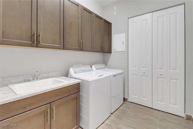 clothes washing area featuring cabinet space, a sink, and washing machine and clothes dryer