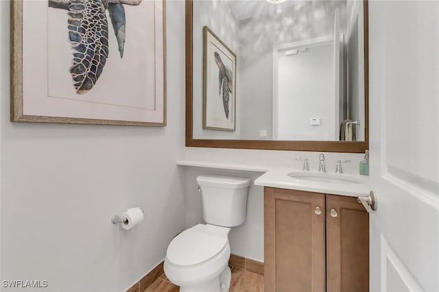 bathroom with toilet, baseboards, and vanity