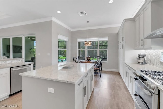 kitchen with a center island, visible vents, decorative backsplash, appliances with stainless steel finishes, and ornamental molding