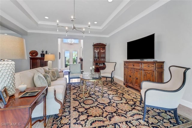 living room featuring a chandelier, a tray ceiling, and baseboards