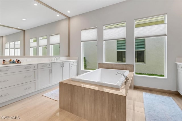 full bathroom featuring recessed lighting, wood finished floors, a bath, and vanity