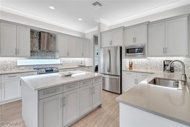 kitchen with stainless steel appliances, visible vents, a sink, a kitchen island, and wall chimney exhaust hood