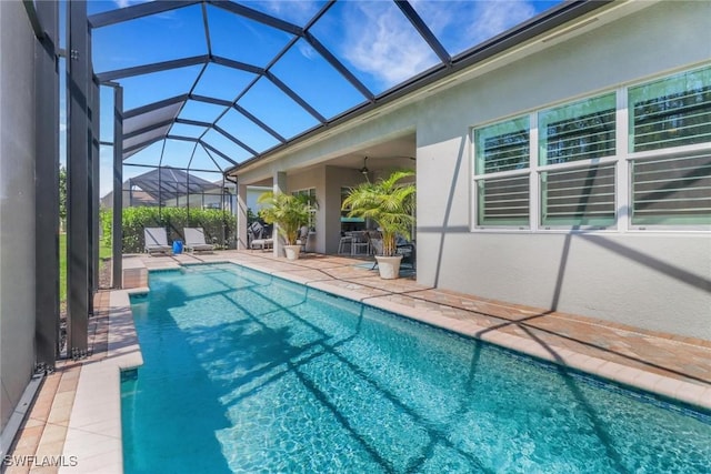 outdoor pool with a lanai, a patio area, and a ceiling fan