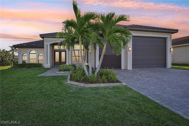 view of front facade featuring stucco siding, french doors, decorative driveway, and a yard