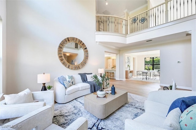 living room featuring crown molding, a high ceiling, wood finished floors, and baseboards