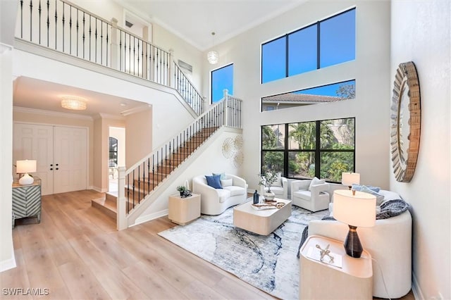 living room featuring baseboards, stairway, ornamental molding, wood finished floors, and a high ceiling