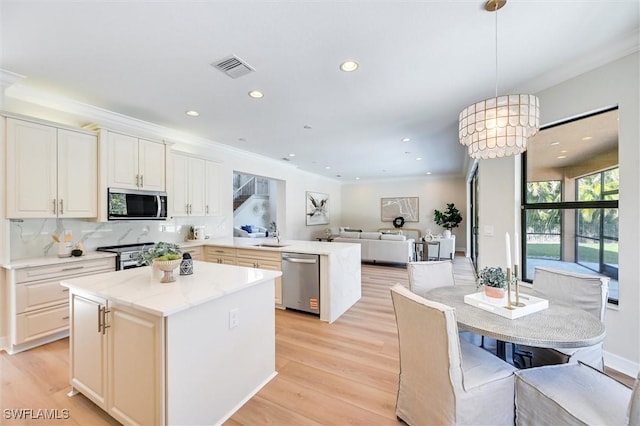 kitchen with stainless steel appliances, tasteful backsplash, light wood-style floors, open floor plan, and a peninsula