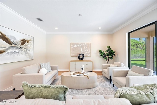 living area featuring baseboards, visible vents, crown molding, and wood finished floors