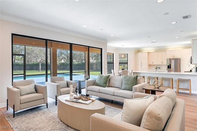 living area with ornamental molding, recessed lighting, and light wood-style floors