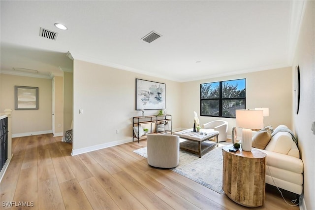 living area featuring baseboards, visible vents, crown molding, and light wood finished floors