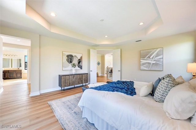 bedroom featuring light wood finished floors, baseboards, a tray ceiling, and recessed lighting