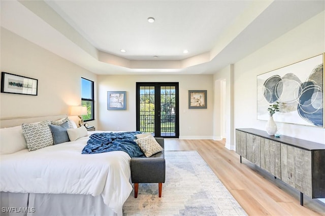 bedroom featuring a tray ceiling, french doors, recessed lighting, light wood-style flooring, and baseboards