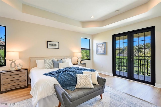 bedroom with a tray ceiling, french doors, wood finished floors, access to outside, and baseboards