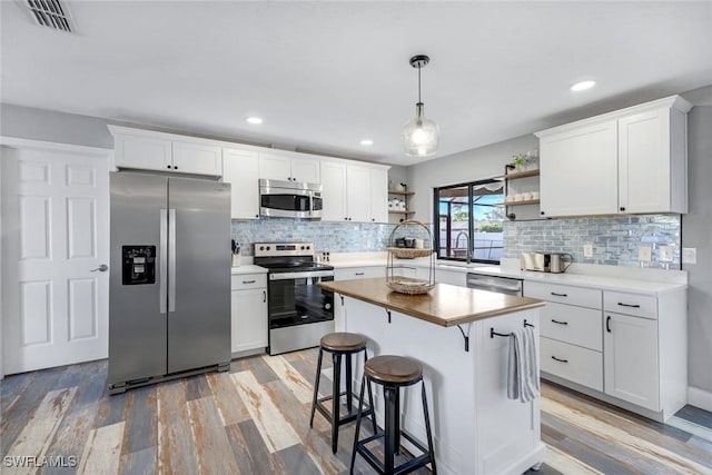 1416 SW 52nd Ter, Cape Coral, FL 33914 - kitchen featuring stainless steel appliances, open shelves, light wood-style flooring, tasteful backsplash, and recessed lighting