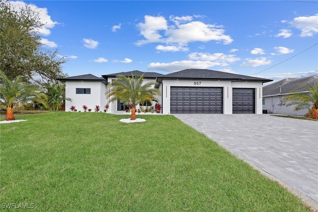 view of front of property with a front yard, decorative driveway, an attached garage, and stucco siding