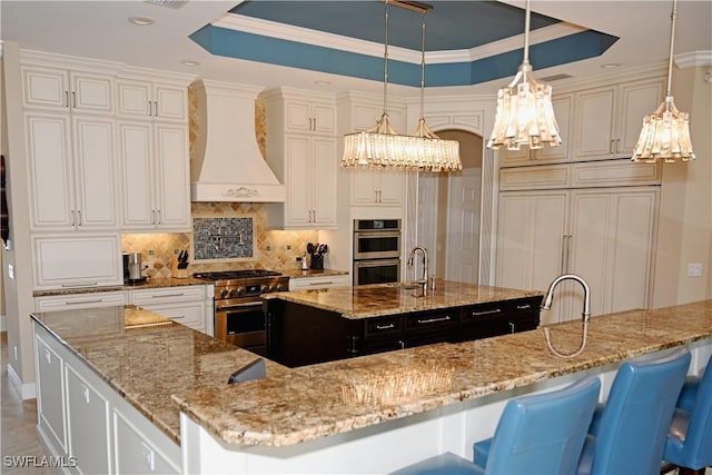 kitchen featuring premium range hood, a spacious island, high quality appliances, tasteful backsplash, and a raised ceiling