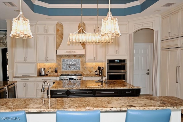 kitchen featuring double oven, stove, decorative backsplash, a raised ceiling, and crown molding