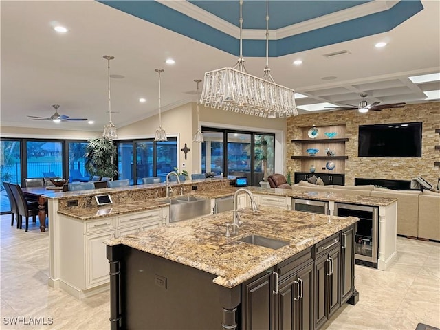 kitchen featuring open floor plan, beverage cooler, a sink, and a large island with sink