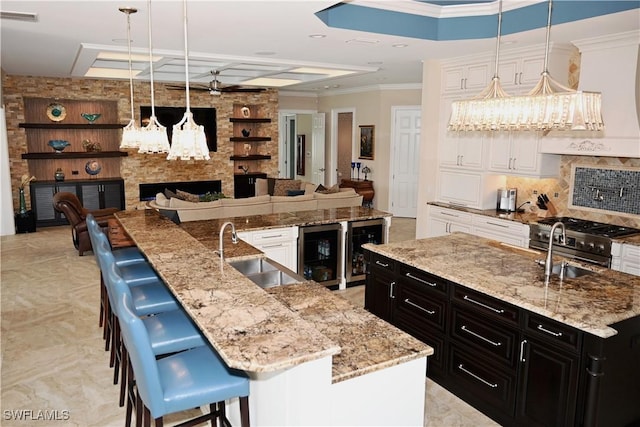 kitchen featuring a large island, a sink, visible vents, and dark cabinets