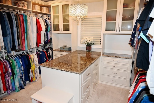 spacious closet featuring a chandelier and light colored carpet