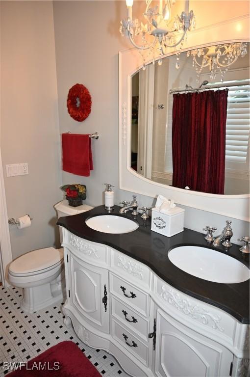 full bathroom with toilet, tile patterned flooring, double vanity, and a sink